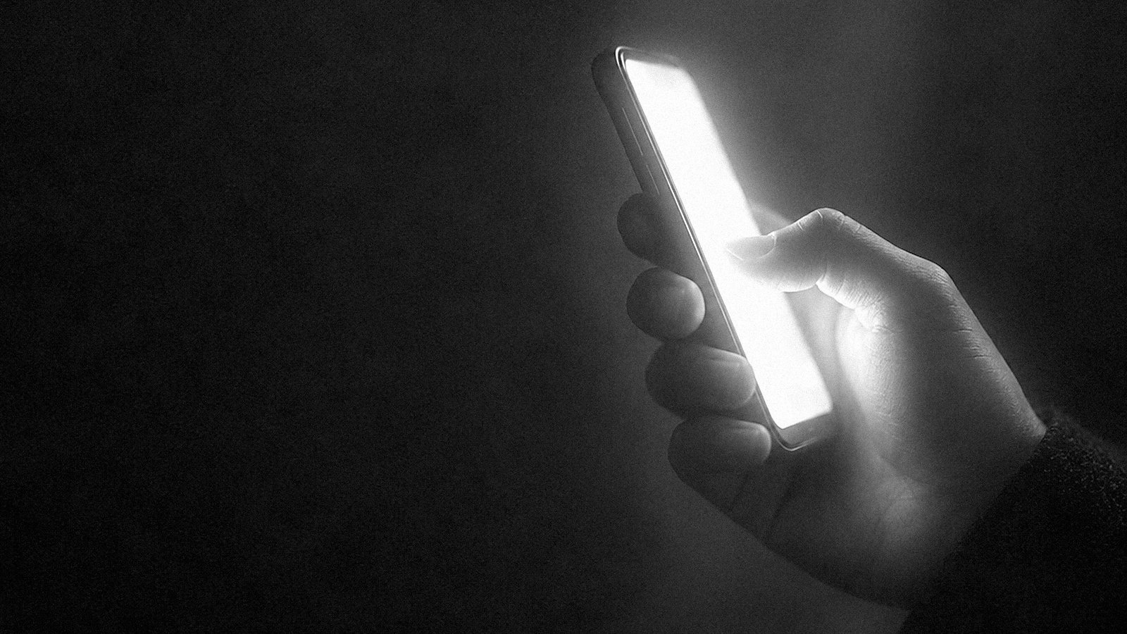 A hand holding a glowing smartphone
